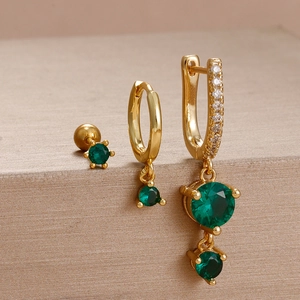 Detailed close-up of golden floral earrings set with emerald green gemstones and diamonds