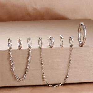 Macro view of silver huggie hoop earrings and ear cuff chain with micro-set zircon