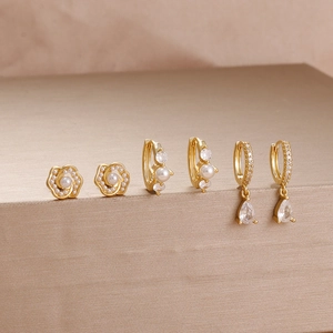 Detailed view of three pairs of gold-plated earrings with pearls and zircon stones