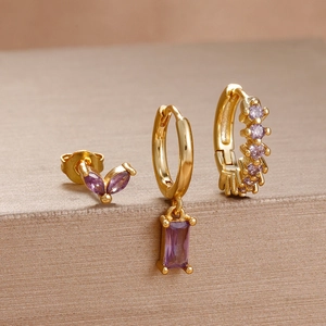 Macro shot of gold-plated piercing studs and earrings set with deep purple gemstones