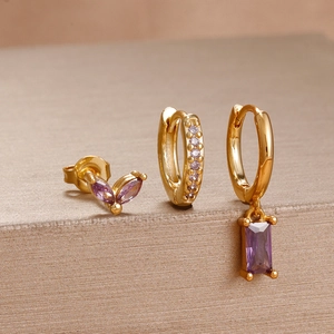 Detailed view of three-piece gold earring set featuring purple cubic zirconia stones
