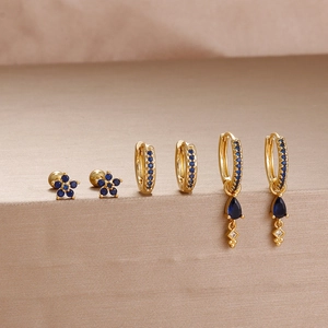 Detailed view of luxury gold earrings set with deep blue sapphire floral and pear drops