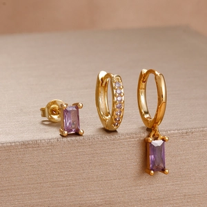 Detailed view of luxury gold earrings set with rectangular purple gemstones and crystals