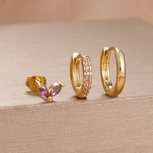 Detail of gold piercing set with butterfly stud and purple zircon-encrusted hoop earrings