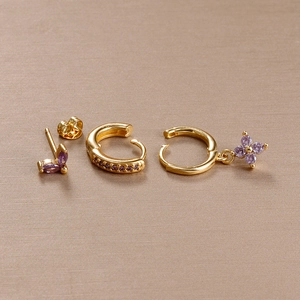 Detailed view of luxury gold earrings set with purple zircon stones and floral pendant