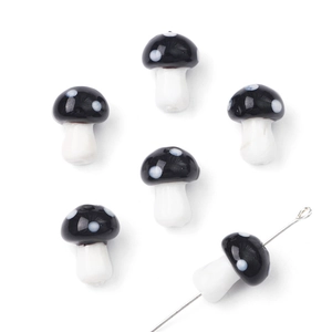 Macro detail of six handmade glass mushroom beads with black and white polka dots