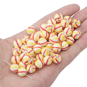 Detailed macro view of hand-painted red and yellow spiral stripe ceramic beads for DIY jewelry