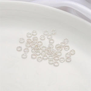 Détail d'anneaux brisés torsadés argentés pour bijoux DIY sur porcelaine blanche