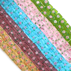 Macro shot of colorful frosted glass cube beads with hand-painted floral patterns for DIY