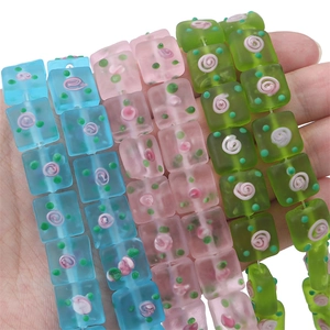 Macro detail of hand-painted matte square glass beads with flower petal patterns