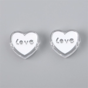 Macro shot of clear acrylic heart beads with silver Love text for DIY jewelry making
