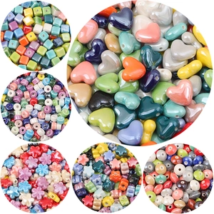 Macro view of colorful glazed ceramic beads in heart, square, and flower shapes for DIY