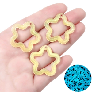 Handheld view showing luminous acrylic star pendants with glitter and blue night glow effect