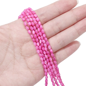 Macro di perle ovali rosa brillante in conchiglia tenute in mano per gioielli fai da te