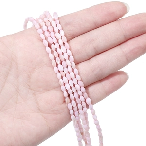 Dettaglio di piccole perle di conchiglia rosa tenute in mano per la creazione di gioielli