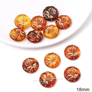 Macro detail of 18mm amber acrylic bead featuring gold floral relief and vintage patterns