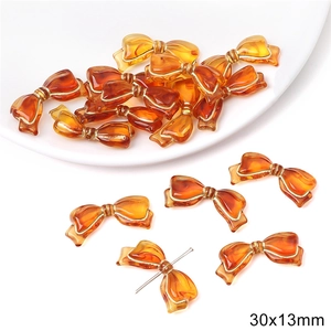 Detailed macro view of 30x13mm amber acrylic bow bead with gold tracing for DIY jewelry