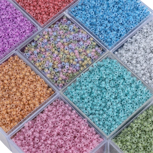 Close-up of assorted colorful glass seed beads organized in a clear plastic storage box