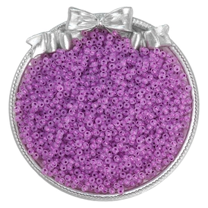 Macro shot of small translucent light purple DIY seed beads in an ornate silver tray
