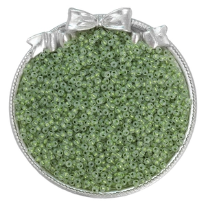 Macro shot of light green translucent seed beads for DIY jewelry making in a silver tray
