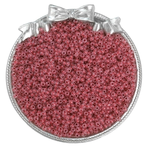 Macro detail of red glass seed beads in a silver bow tray for DIY jewelry making