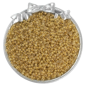 Close-up of golden glass seed beads in a silver tray for DIY jewelry making crafts