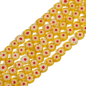 Macro detail of yellow millefiori glass beads with red and white floral patterns for DIY