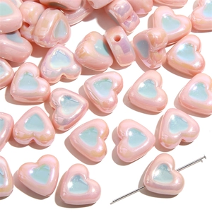Macro detail of pastel pink acrylic heart beads with iridescent finish and center hole