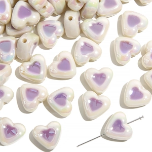Macro detail of acrylic heart beads with purple center and iridescent finish for DIY jewelry