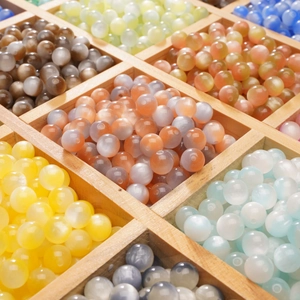Colorful resin cat-eye acrylic beads in a wooden organizer for DIY jewelry making