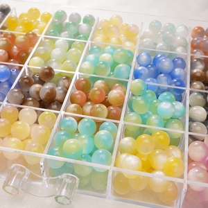 Detailed close-up of colorful cat-eye resin beads sorted in a clear plastic grid box