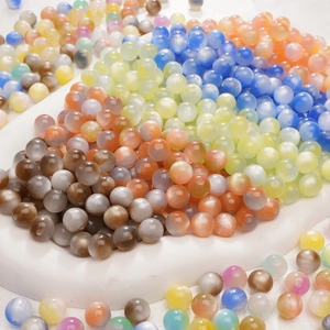 Macro shot of colorful cat eye resin beads on marble tray for DIY jewelry making