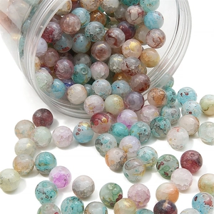 Macro shot of ink-textured glass beads with gold specks spilling from a clear jar