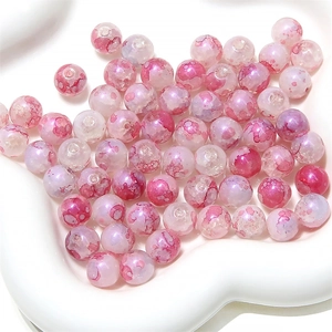 Gros plan de perles en verre aurore rose avec effet d'encre dans un plat en cœur blanc