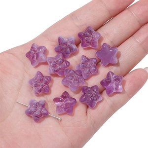 Detailed view of purple star-shaped glass beads for handmade jewelry on a palm