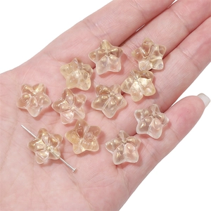 Macro detail of transparent star-shaped glass beads with gold foil foil in hand