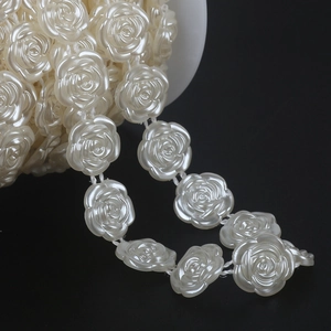 Macro shot of cream white pearl rose bead chain on a spool for DIY bridal dress trim