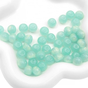Macro shot of mint green translucent resin beads for DIY jewelry in ceramic dish