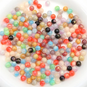 Perles colorées en résine étoilée pour création de bijoux DIY dans un bac