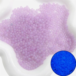 Détail macro de perles en verre lavande 2-3mm montrant l'effet fluorescent bleu sous UV
