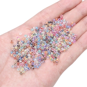 Mixed 2-4mm iridescent glass seed beads for DIY jewelry making held in a palm
