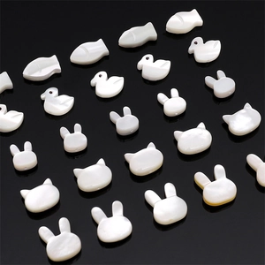 Macro detail of white animal-shaped shell beads for DIY jewelry on a black background