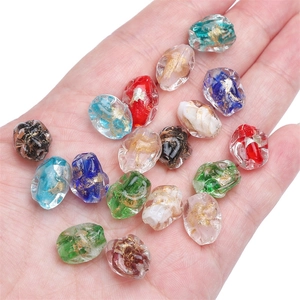 Irregular handmade glass beads with gold foil foil held in hand for DIY jewelry making