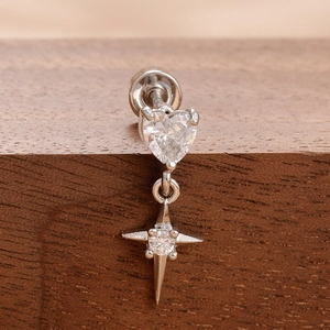 Macro shot of silver heart zircon and North Star pendant screw-back earring on wood