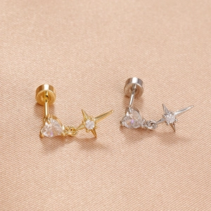 Detail of gold and silver heart-shaped zircon earrings with North Star pendants on silk