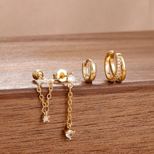 Detalle del juego de 4 pendientes de latón dorado con circonitas sobre madera