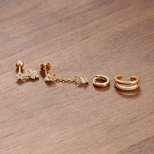 Detalle del juego de pendientes de latón dorado con flor de circón y earcuff