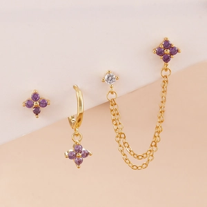 Detailed shot of four-piece gold earring set with purple flowers and zircon tassels