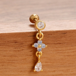 Detalle macro de piercing para ombligo dorado con flor azul y colgantes de circón
