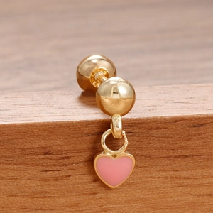 Detalle macro de un pendiente dorado con un colgante de corazón esmaltado en rosa